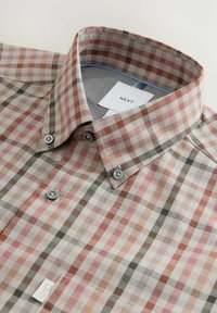 Camicia a quadri nelle tonalità di rosa, beige e verde con colletto abbottonato. Bottoni grigio chiaro e un'etichetta con la scritta "NEXT" visibile.