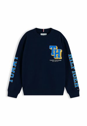 Marineblauwe crewneck trui met grote blauwe en gele "TH" letters en Tommy Hilfiger branding op voorkant en mouwen.