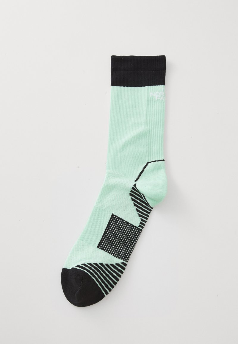 Calcetín verde menta con puño de canalé negro, acentos estampados y texturas estructuradas. Presenta puntera negra y elementos de diseño geométrico.