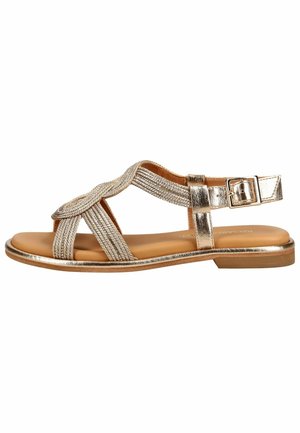 Sandalia plana con tiras metálicas de textura trenzada, puntera abierta y cierre ajustable de hebilla sobre una suela color canela.