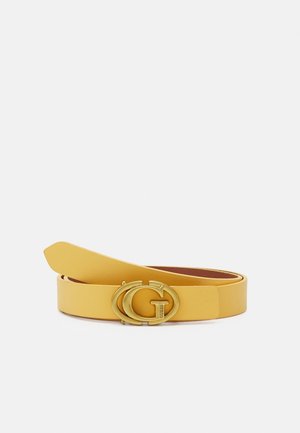 Gult læderbælte med guldfarvet dobbelt "G" spænde indgraveret med "GUESS", rullet på hvid baggrund.