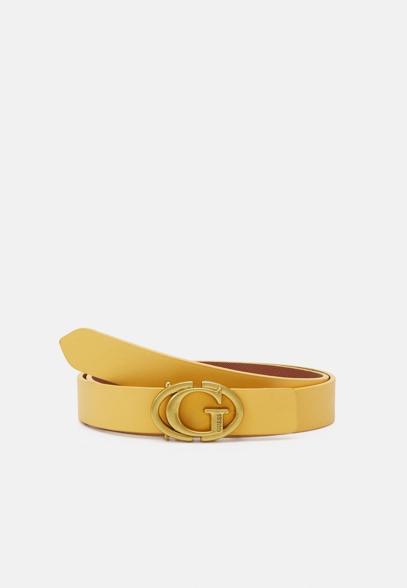 Ceinture en cuir jaune avec boucle double "G" dorée gravée "GUESS", roulée sur fond blanc.