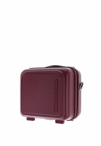 Valigia da cabina rigida compatta di colore marrone scuro con manico e cerniera, poggiata su piccoli piedini.