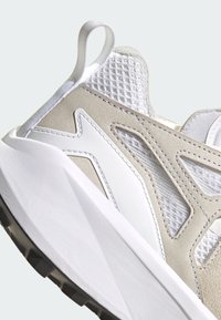 Light gray athletic shoe with mesh and suede upper, white rubber sole, padded collar, and a textured loop pull tab on the heel.