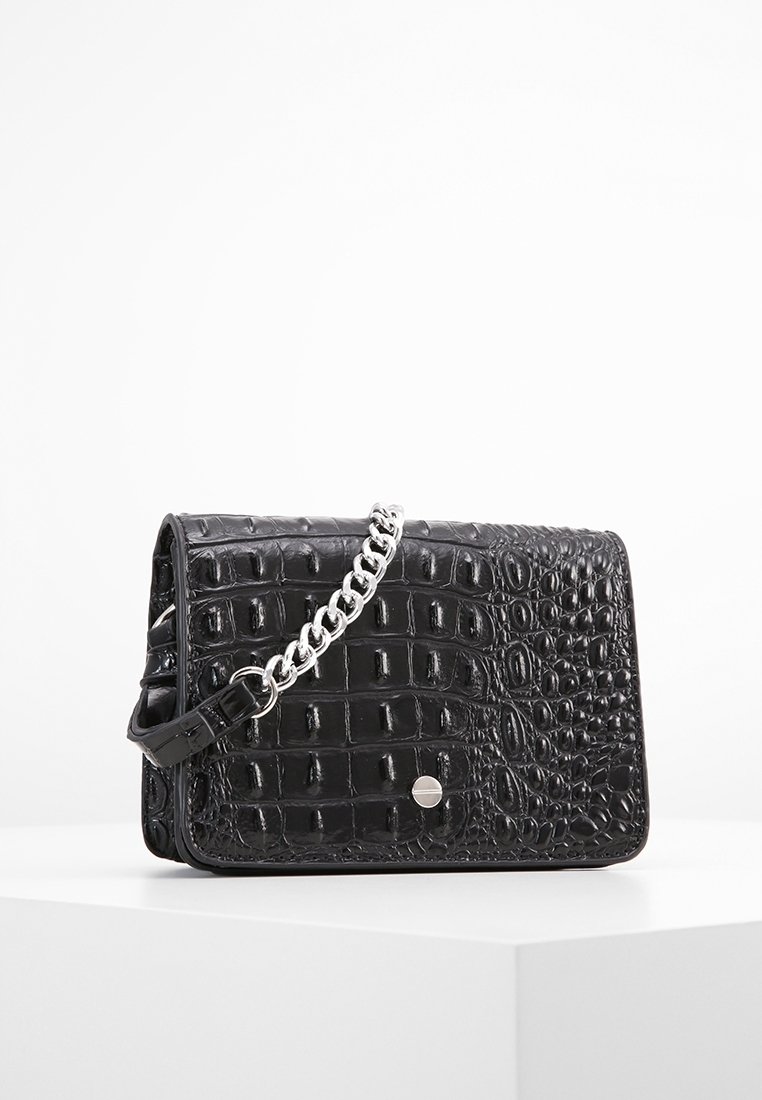 Borsa crossbody in pelle sintetica nera con texture coccodrillo, tracolla in catena argentata e un piccolo dettaglio con bottone a pressione sul davanti.