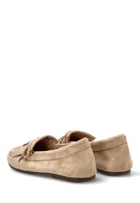 Mocasines de ante beige con una textura suave, punta redondeada y un detalle decorativo de lazo en la parte superior. Suela de goma plana para un uso fácil.