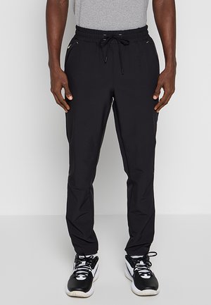 Czarne sportowe spodnie z elastycznym pasem i regulowanym sznurkiem. Posiadają kieszenie boczne oraz zwężany krój nogawek. Gładka tekstura.
