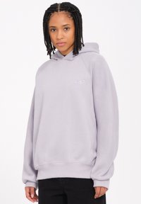 Haut à capuche gris clair avec une coupe d écontractée, des poignets et un ourlet côtelés, et un petit logo brodé sur la poitrine. Tissu au toucher doux.