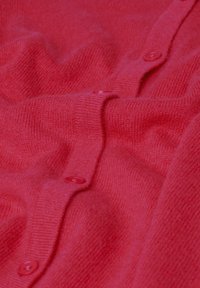 Rode cardigan gemaakt van zacht materiaal met een gestructureerde afwerking, voorzien van een rij ronde, bijpassende knopen in het midden.