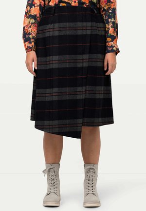 Krótka spódnica do kolan w czarno-szarą kratę, noszona z jasnoszarymi sznurowanymi botkami za kostkę oraz kwiecistą bluzką z długim rękawem.