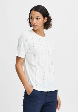 Haut blanc à manches courtes avec un motif tricoté texturé présentant des détails ajourés. Encolure ronde et coupe décontractée, associé à un pantalon bleu marine.
