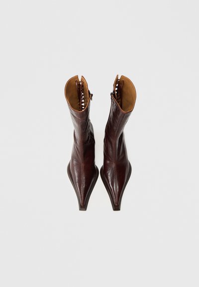 Καφέ �δερμάτινα μποτάκια μέχρι τον αστράγαλο με μυτερά δάχτυλα, λεία επιφάνεια και αντίθετη ταμπά εσωτερική επένδυση. Περιλαμβάνει πλευρικό φερμουάρ και διακοσμητική ραφή.
