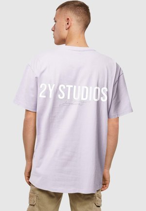 Hellblaues Baumwoll-T-Shirt mit kräftigem weißen Schriftzug "2Y STUDIOS" auf dem Rücken. Lockere Passform, kurze Ärmel und runder Ausschnitt.