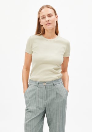 Camiseta ajustada de color verde claro con mangas cortas, combinada con pantalones de talle alto a rayas grises que cuentan con cierre de botón y bolsillos laterales.