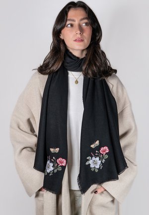 Zwarte sjaal met geborduurde bloemen- en vlinderontwerpen in rood, blauw en groen. Zachte textuur met franjes aan de uiteinden.
