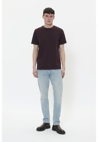 Camiseta de algodón burdeos combinada con jeans azul claro y botas negras al tobillo. Diseño simple con mangas cortas, sin patrones ni acentos.