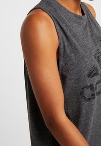 Tmavě šedý bezrukávový top s kulatým výstřihem, s jemnou texturou a decentním potištěným vzorem na přední straně.