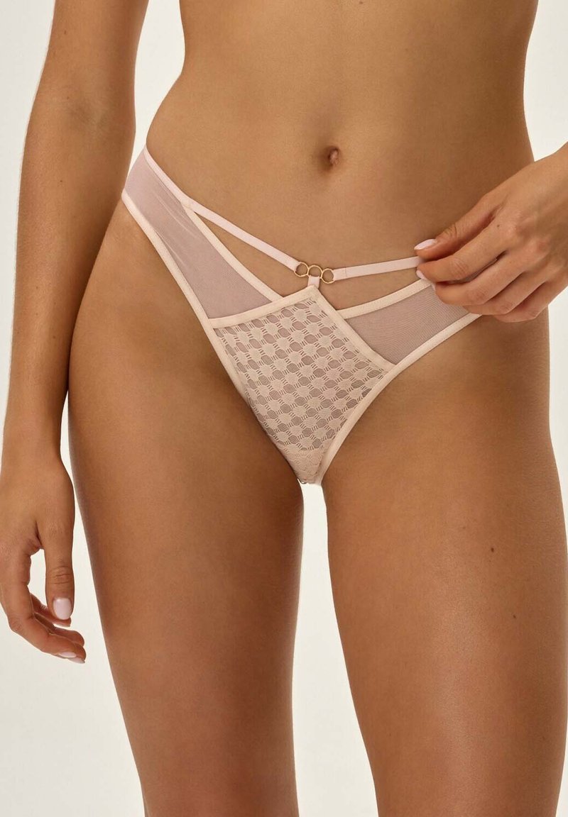 Naga bielizna wykonana z koronkowego wzoru, przezroczystej siateczki i podwójnych ramiączek z złotymi akcentami. Zaprojektowana w niskim kroju i miękkiej teksturze.