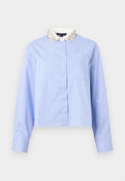 Ανοιχτό μπλε μπλούζα με μακριά μανίκια, λεπτές κάθετες λευκές και μαύρες ρίγες, τσέπη μπροστά και λευκό γιακά διακοσμημένο με μαργαριτάρια και χάντρες.