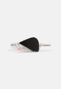Chaussure à talon aigu transparent avec un motif imprimé de journal, vue de dessous, mettant en valeur la semelle noire et le talon transparent.