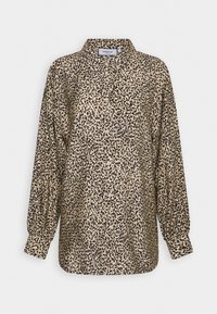 Blouse boutonnée à manches longues avec un motif tacheté irrégulier beige et noir et des poignets froncés.