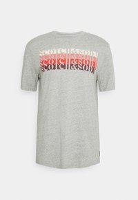 Grå T-shirt med korte ærmer lavet af blødt stof, der har et iøjnefaldende grafisk print i rød, sort og creme over brystet. Teksten er stiliseret.