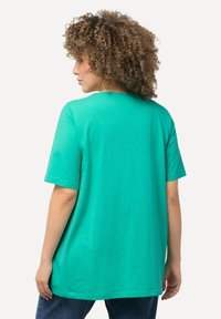 T-shirt in cotone turchese con maniche corte, scollatura rotonda e vestibilità comoda. Presenta un delicato dettaglio della cucitura sul retro.