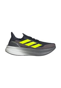 Chaussure de sport noire et grise avec trois rayures jaunes audacieuses, un dessus texturé et une épaisse semelle intermédiaire blanche au fini lisse.