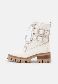 Botas blancas hasta el tobillo con textura acolchada, doble hebilla, cordones redondos y un tacón de madera grueso con suela dentada.