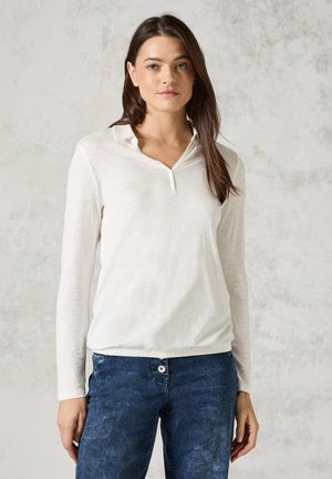 Witte lange mouwen shirt met een kraagrand, voorzien van een zachte textuur en een ontspannen pasvorm, gecombineerd met donkerblauwe denim jeans.