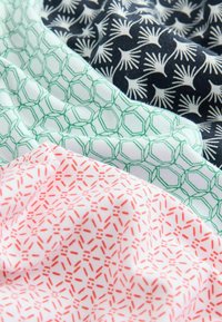 Kolm volditud kangast näidist: tumehall põhja valge lillemustriga, piparmündiroheline kuhexagonaalne ruudustik ning valge põhja punase geomeetrilise mustriga.