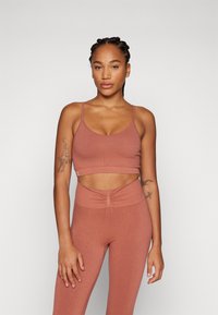 Rustfarget ribbet sport-bh med tynne stropper og kort design, parret med matchende høyt midje leggings med rynkedetaljer.