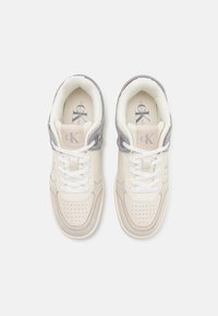 Sneaker bianche e grigio chiaro con design in pelle e sintetico, punta perforata, chiusura con lacci e supporto imbottito alla caviglia.