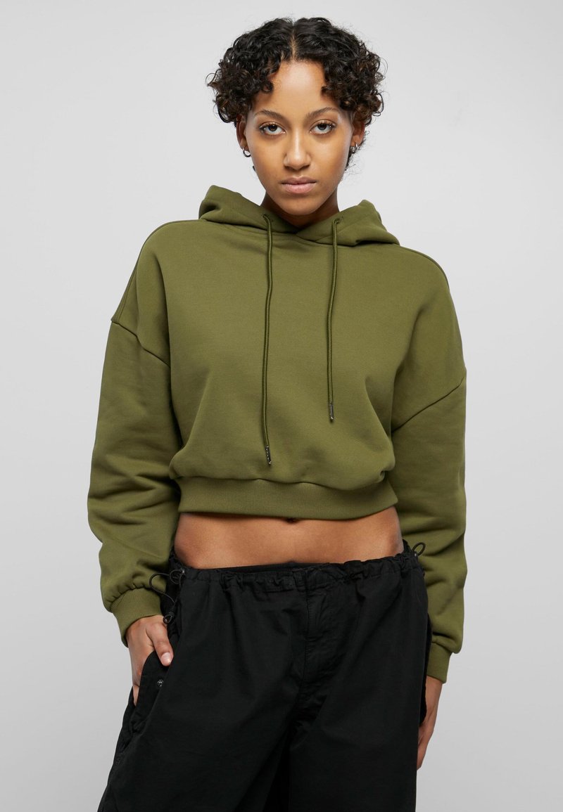 Olive green cropped hoodie with drawstring, relaxed fit, and long sleeves, paired with black loose-fitting pants. Smooth texture, minimal design.