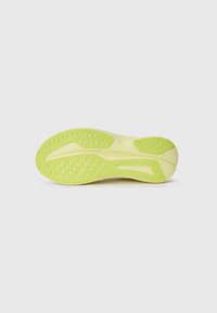 Semelle de chaussure d'une couleur jaune-vert vif, avec un motif texturé et de petites perforations pour l'adhérence. Bords lisses et forme ergonomique.