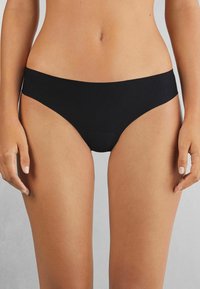 Svart bikiniunderkläder med en mjuk textur och minimalistisk design. Har en låg midja och sömlösa kanter, vilket ger en bekväm passform.