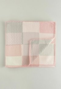 Knit blanket featuring a patchwork design in soft pink, light gray, and white colors. Textured squares and a folded edge accentuate the design.