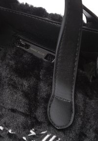 Borsa nera con una texture morbida, con dettagli in pelle e un'etichetta in rilievo con la scritta "MARC ELLIS." L'interno presenta una morbida fodera nera.