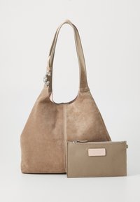 Borsa a tracolla in suede color sabbia con texture liscia, forma arrotondata e manico corto. Include un sacchetto in pelle coordinato con chiusura a zip.
