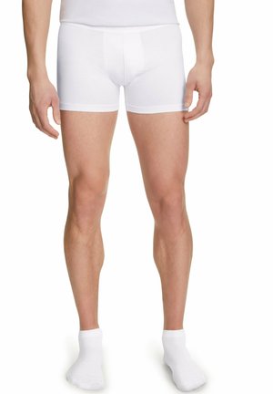 Witte katoenen boxershorts met een gladde textuur, aansluitend ontwerp en elastische tailleband. Model met witte enkelsokken.
