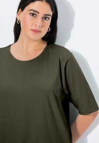 Dunkelolivgrünes Kurzarm-T-Shirt aus weichem Stoff, mit rundem Halsausschnitt und lockerer Passform. Glatte Textur, minimalistisches Design.