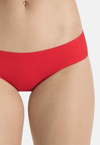 Roter Bikiniunterteil aus glattem Material, mit einem tief sitzenden Design und einfacher Konstruktion ohne Verzierungen oder Muster.