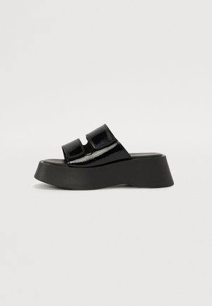 Black patent leather platform sandals with two adjustable straps. Features a thick black sole with a wedge shape and smooth texture.