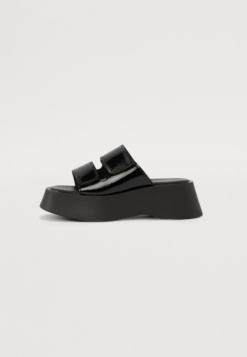 Black patent leather platform sandals with two adjustable straps. Features a thick black sole with a wedge shape and smooth texture.