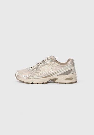 Beige og lysebrun New Balance atletiksko med mesh-overdel, snørelukning og polstret sål på neutral baggrund.