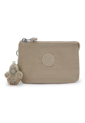Beige fabric zip pouch with circular logo patch and attached fluffy keychain shaped like a small ape or monkey.