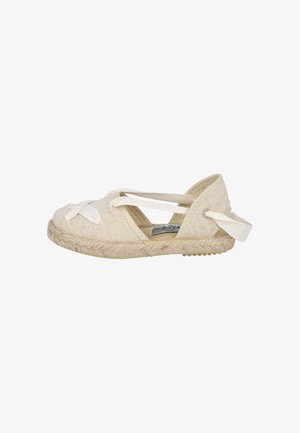 Zapato espadrille plano de lona beige con suela de yute trenzado y tiras de tela cruzadas sobre la parte superior y alrededor del talón.