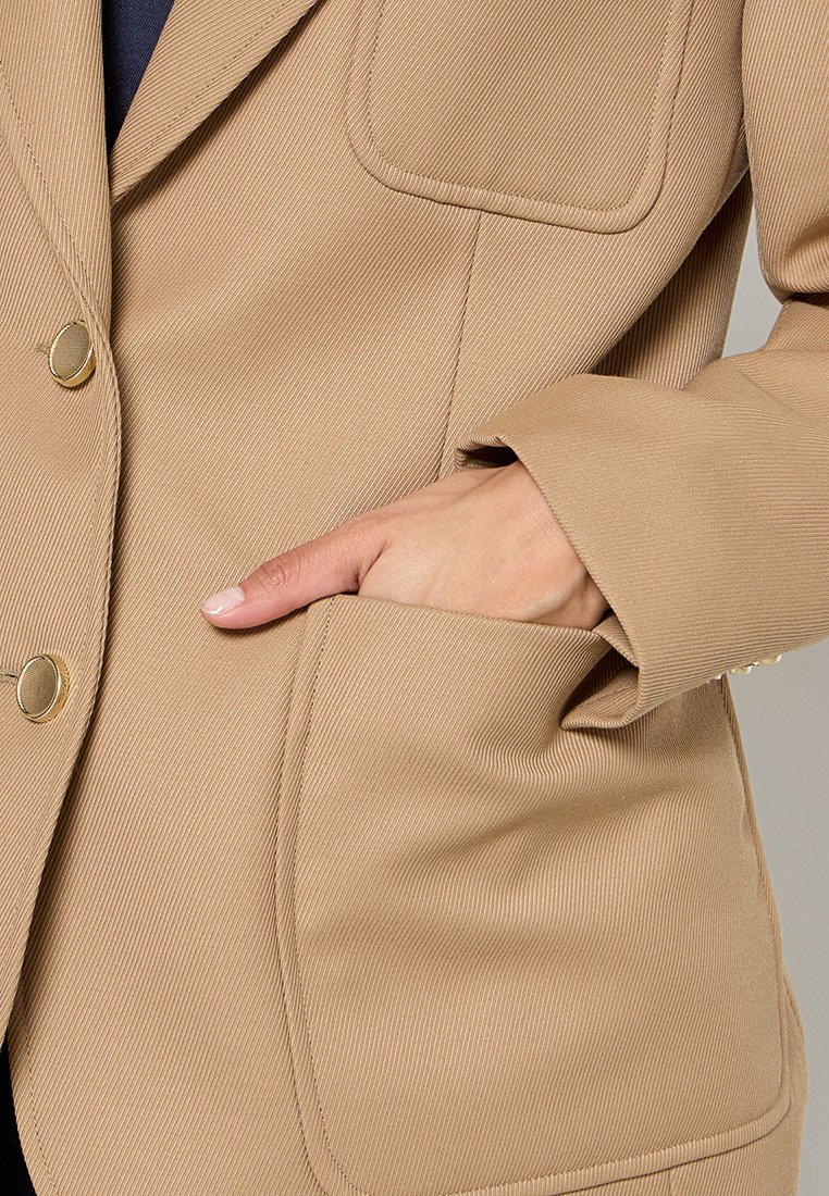 Beige blazer met een gestructureerde stof, klepzak, en gouden knopen, met een getailleerde pasvorm en licht gestructureerde schouders.