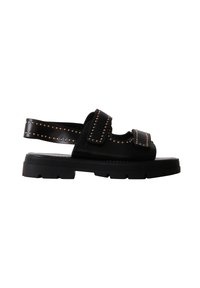 Sandale à semelle épaisse noire avec deux bandes Velcro et de petits clous ronds en bronze le long des bandes et de la bride arrière.