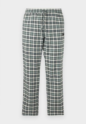 Pantalon à taille élastique à carreaux verts, noirs et blancs avec un cordon de serrage et une petite étiquette de marque noire sur le côté droit.